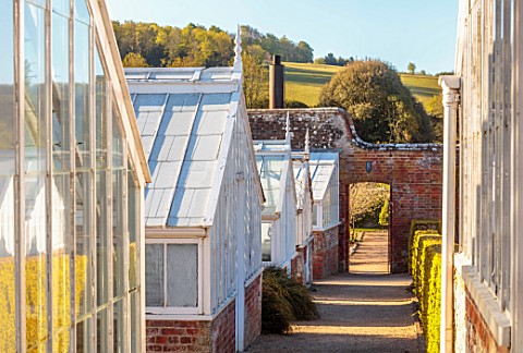 WEST_DEAN_GARDENS_WEST_SUSSEX_GREENHOUSES_WITH_COUNTRYSIDE_BEYOND_MAY_SPRING_GLASSHOUSES_GARDEN_BUIL