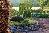 SILVER STREET FARM, DEVON. DESIGNER ALASDAIR CAMERON: JUNE, EARLY MORNING, BORDERS, HEDGES, HEDGING, WALLS, YEW DOME, CLIPPED, TOPIARY, SEDUMS, TERRACOTTA CONTAINER