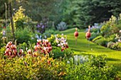 COTON MANOR, NORTHAMPTONSHIRE: IRISES IN BORDER, GRASS PATH, FLAMINGOS, MAY, SPRING, PINK, RED FLOWERS