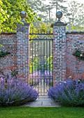 VEN HOUSE, SOMERSET: THE WALLED GARDEN, VIEW THROUGH ORNATE METAL GATES TO PEAR TUNNEL, NEPETA SIX HILLS GIANT, BLUE, PURPLE FLOWER, JUNE, SUMMER