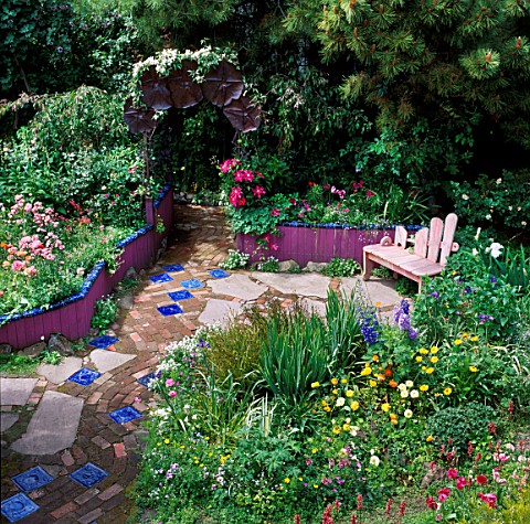 LOOKING_DOWN_ON_GARDENPATH_WITH_INSET_BLUE_TILESWOODEN_SEATRAISED_BEDS__BORDERS_DESKEEYLA_MEADOWSSAN