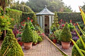 WOLLERTON OLD HALL, SHROPSHIRE: PATH, SEPTEMBER, SUMMERHOUSE, SHED, OFFICE, OUTDOOR, OUTSIDE, CLIPPED TOPIARY, CONTAINERS, DAHLIAS, DAHLIAS, PETUNIAS, HEDGES, HEDGING