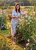 ASHBROOK HOUSE, NORTHAMPTONSHIRE: DESIGNER JOSEPHINE MAYDON IN VEGETABLE GARDEN, POTAGER, SUNSET, EVENING LIGHT, WILLOW TUNNELS OF SWEET PEAS, WOODEN BENCH, VEGETABLES, CUTTING