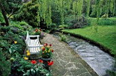 WEEPING WILLOW FRAMES VIEW OF WOODEN SEAT BACKING ONTO ROCK GARDEN BESIDE THE STREAM. MR & MRS STYLES GARDEN  OXON