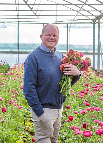 SMITH__MUNSON_LINCOLNSHIRE_STEPHEN_MUNSON_HOLDING_RANUNCULUS_IN_A_GREENHOUSE