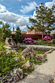 CHELSEA 2022: A SWISS SANCTUARY BY LILLY GOMM: PATH, ALPINE PLANTING, ROCKS, WATERFALL, RHODODENDRONS, METAL SEAT, POOL, POND, WATER