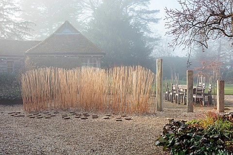 LONGYARD_COTTAGE_ESSEX_WINTER_FEBRUARY_MIST_FOG_FOGGY_WOODEN_TABLE_CHAIRS_CUT_MISCANTHUS_STEMS_WOODE