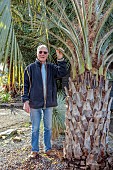 THE PALM CENTRE, LONDON: MARCH, OWNER MARTIN GIBBONS BESIDE TWO SPECIMENS OF BUTIA ODORATA
