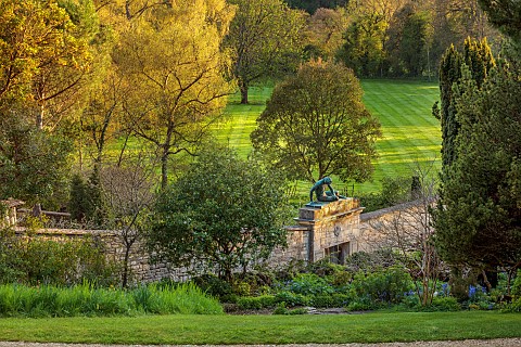 IFORD_MANOR_WILTSHIRE_APRIL_VIEW_DOWN_GARDEN_TO_WALL_AND_STATUE_OF_DYING_GAUL_BORROWED_LANDSCAPE