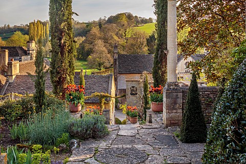 IFORD_MANOR_WILTSHIRE_APRIL_STEPS_TO_TOP_TERRACE_TERRACOTTA_CONTAINERS_WITH_TULIPS_LANDSCAPE_BORROWE