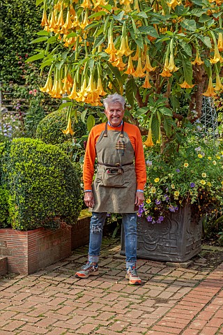 EAST_RUSTON_OLD_VICARAGE_GARDEN_NORFOLK_ALAN_GRAY_STANDS_IN_THE_DUTCH_GARDEN_BENEATH_A_LARGE_YELLOW_