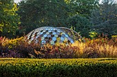 GRANTLEY HALL, YORKSHIRE: SUNSET, LAWN, BORDERS, GRASSES, STIPA GIGANTEA, PATINATED STEEL AND COLOURED STAINLESS STEEL GLAZED CUPOLA SEAT, SEPTEMBER