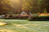 GRANTLEY HALL, YORKSHIRE: LIGHTING, DAWN, BOX EDGED BEDS, WATER, POOL, PATINATED STEEL AND COLOURED STAINLESS STEEL GLAZED CUPOLA SEAT, BORDERS, GRASSES, SEPTEMBER