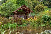 SIR HAROLD HILLIER GARDENS, HAMPSHIRE: OCTOBER, FALL, AUTUMN, ARBORETUM, POND, WATER, POOL, RED, WOODEN VIEWING PLATFORM, BUILDING, SEATING, BALCONY