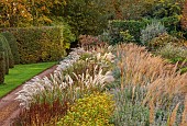 BROUGHTON GRANGE GARDENS, OXFORDSHIRE: FALL, AUTUMN, OCTOBER, PARTERRE, GRASSES, STIPA CALAMAGROSTIS, TREES, CLIPPED YEW