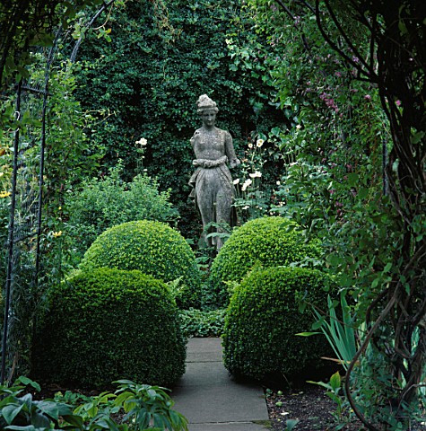 ARCHES_AND_CLIPPED_BOX_BALLS_CREATE_VISTA_TO_STATUE_OF_DIANA_IN_SHADY_CORNER_DESIGNER_HELEN_DILLON