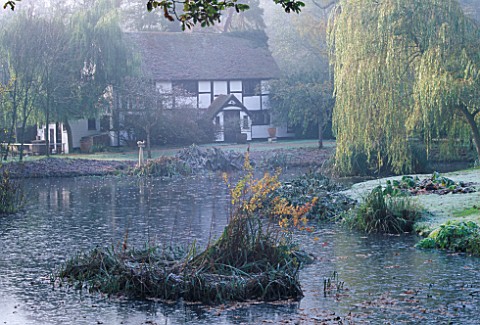 BLACK_AND_WHITE_COTTAGE_SEEN_ACROSS_THE_LAKE_THE_HANNAH_PESCHAR_GALLERY_AND_SCULPTURE_GARDEN__SURREY