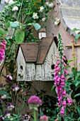 ORNATE HOUSE-STYLE BIRD BOX SURROUNDED BY FOXGLOVES. DESIGNER BUNNY GUINNESS/DGAA HOMELIFE GARDEN CHELSEA 97