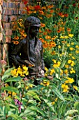 STATUE OF SMALL BOY AMIDST YELLOW PLANTING OF HELENIUMS  CROCOSMIA  COREOPSIS AND OENOTHERA IN THE RAILWAY CHILDRENS GARDEN  HAMPTON COURT 97. DESIGNER: PAUL STONE.