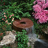 WATER FEATURE: MILLSTONE WATERFALL SURROUNDED BY FERNS  RHODODENDRONS AND AQUILEGIAS. DAILY MIRROR GARDEN  CHELSEA 1994