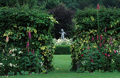VIEW_THROUGH_GAP_IN_PINK_BORDER_TO_WHITE_GARDEN_AND_STATUE_OF_CUPID_CHENIES_MANOR__BUCKINGHAMSHIRE
