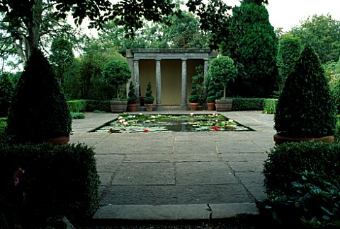 FORMAL_LILY_POND_IN_CENTRE_OF_PAVED_AREA_IN_FRONT_OF_STONE_PAVILION__CONTAINERS_WITH_TOPIARY_BALLS_A