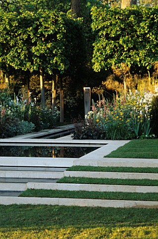 STEPPED_WATER_FEATURE_WITH_STONE_EDGING_AND_LAWN_METAL_RECTANGULAR_SCULPTURE_AS_FOCAL_POINT__EVENING