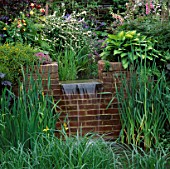 WATER FEATURE: SMALL WATERFALL OVER BRICK WALL INTO LILY POND SURROUNDED BY MARGINALS