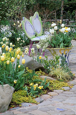 DOGWOOD_BUTTERFLY_BENCH_BY_KEEYLA_MEADOWS_BESIDE_A_CERAMIC_POT_PLANTED_WITH_WHITE_TULIPS_DESIGNER_KE