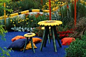 FISHER PRICE CHILDRENS GARDEN DESIGNED BY SARAH EBERLE. HAMPTON COURT FLOWER SHOW 1998. SUNFLOWER CHAIRS AND TABLE AND BLUE SILICONE PATH