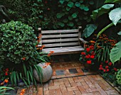 BRICK COURTYARD WITH STONE BALL  CROCOSMIA AND WOODEN BENCH.  DESIGN: ANDREW & KARLA NEWELL