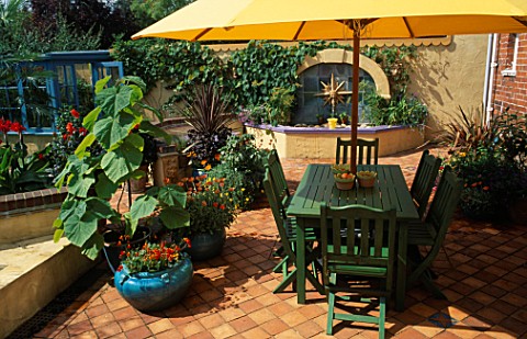 GREEN_TABLE_AND_CHAIRS_ON_TERRACOTTA_PATIO_WITH_WATER_EFATURE_BEHIND_AND_CALCEOLARIA_F1_HYBRID_SUNSE