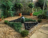KNOT GARDEN WITH GRAVEL  PEBBLES  BLACK OPHIOPOGON GRASS  FESTUCA GLAUCA AND A GREEN GLAZED POT IN THE CENTRE