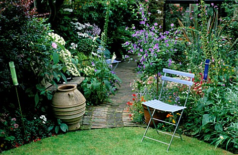CHAIR_IN_SECLUDED_SPOT_AT_EDGE_OF_LAWN_WITH_BRICK_PATH_LEADING_TO_SHADY_PART_OF_SMALL_TOWN_GARDEN__C
