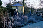 THE SUMMERHOUSE GARDEN AT ARROW COTTAGE IN THE FROST. BLUE WOODEN TRIPOD IN FOREGROUND AND THE TOWER BEHIND