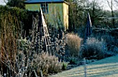 THE SUMMERHOUSE GARDEN AT ARROW COTTAGE IN THE FROST. BLUE WOODEN TRIPOD IN FOREGROUND AND THE TOWER BEHIND
