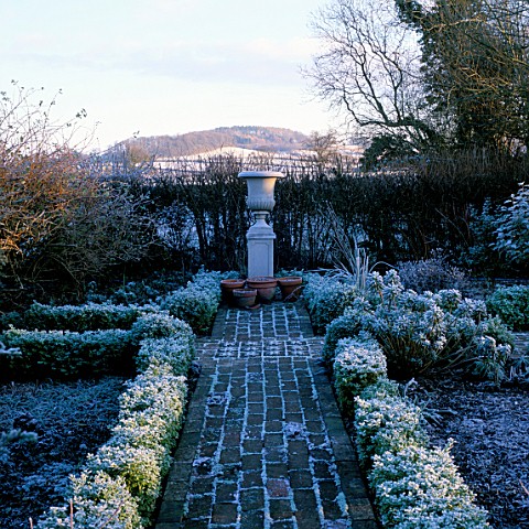 EARLY_MORNING_FROSTY_VIEW_DOWN_A_BOX_EDGED_BRICK_PATH_TO_A_STONE_URN_WITH_THE_HILLS_BEYOND__ARROW_CO