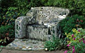 A CEMENT SOFA EMBROIDERED WITH MIRROR FRAGMENTS AND MARBLES IN ROBERT CLARKS SAN FRANCISCO GARDEN. THE SEAT WAS DESIGNED BY RAUL ZUMBA
