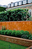 VIEW OF ITALIAN POLISHED PLASTER WALL BACKS RAISED BED WITH BOX BALLS. MODERNISTS TOWN GARDEN