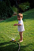 WILLIAM PLAYING WITH A HOSEPIPE IN THE GARDEN. THE NICHOLS GARDEN  READING