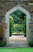 ARCHWAY IN BRICK WALL LOOKING THROUGH TO THE ROUND POND AND RECYCLING WATER TROUGHS. WITH ROSA IN THE BACKGROUND. THE ABBEY HOUSE  WILTSHIRE.