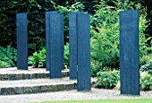 SIX UPRIGHT SLATE SLABS FORM A SCULPTURAL FOCAL POINT ON THE STEPS OF THE PLANTSMAN AND FOLIAGE GARDEN AT ROSEMOOR. DESIGNED BY TOM STUART-SMITH.
