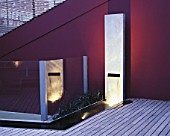ROOF GARDEN WITH LIGHTING: TIMBER DECKING  RENDERED WALL PAINTED AUBERGINE  WATER FEATURE MADE FROM GALVANISED STEEL BLOCK AND SUNKEN RILL. DESIGNERS PAUL THOMPSON/TREVYN MCDOWELL