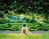 VIEW FROM THE KNOT GARDEN (WITH TOPIARY IN TERRACOTTA CONTAINERS) TO THE ROSE WALK IN THE EARLY MORNING SUNSHINE. NYEWOOD HOUSE   WEST SUSSEX.