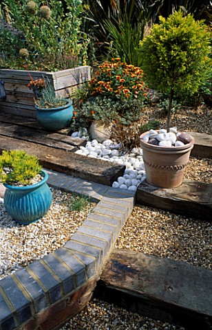 VIEW_ACROSS_THE_SHINGLE_GARDEN_TOWARDS_THE_WOODEN_HERB_SEAT_WITH_SLEEPERS_ACTING_AS_STEPS__TOPIARY__