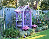 NICHOLS GARDEN: COVERED WOODEN SEAT SURROUNDED BY SILVER PAINTED METAL STANDS AND TWO URNS PLANTED WITH AGAVES. IN TWO POTS ARE PINK CHRYSANTHEMUMS. NICHOLS GARDEN  READING