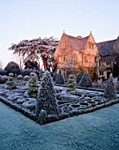 VIEW ACROSS THE FROSTED CELTIC KNOT GARDEN WITH TOPIARY  TOWARDS THE SUNLIT HOUSE. THE ABBEY HOUSE  WILTSHIRE.