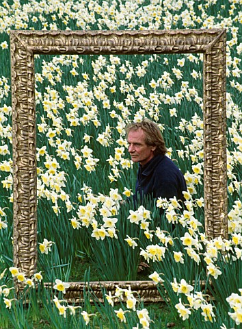 DESIGNER__IVAN_HICKS_POSES_INSIDE_AN_ORNATE_PICTURE_FRAME_SURROUNDED_BY_NARCISSUS_ICE_FOLLIES_GROOMB