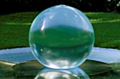 WATER FEATURE: TRANSPARENT GLASS SPHERICAL FOUNTAIN AT THE CENTRE OF A ROUND POND IN THE LAWN. HOMES & GARDENS THE GARDEN OF REFLECTION. CHELSEA FLOWER SHOW 2000.