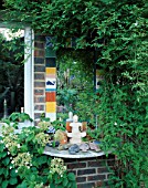 MIRROR ON HOUSE WALL WITH CERAMIC TILE SURROUND. ROBIN GREEN AND RALPH CADES SEASIDE STYLE GARDEN  LONDON
